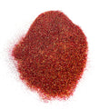A pile of glitter with hues of red/orange/bronze/gold on a white background.