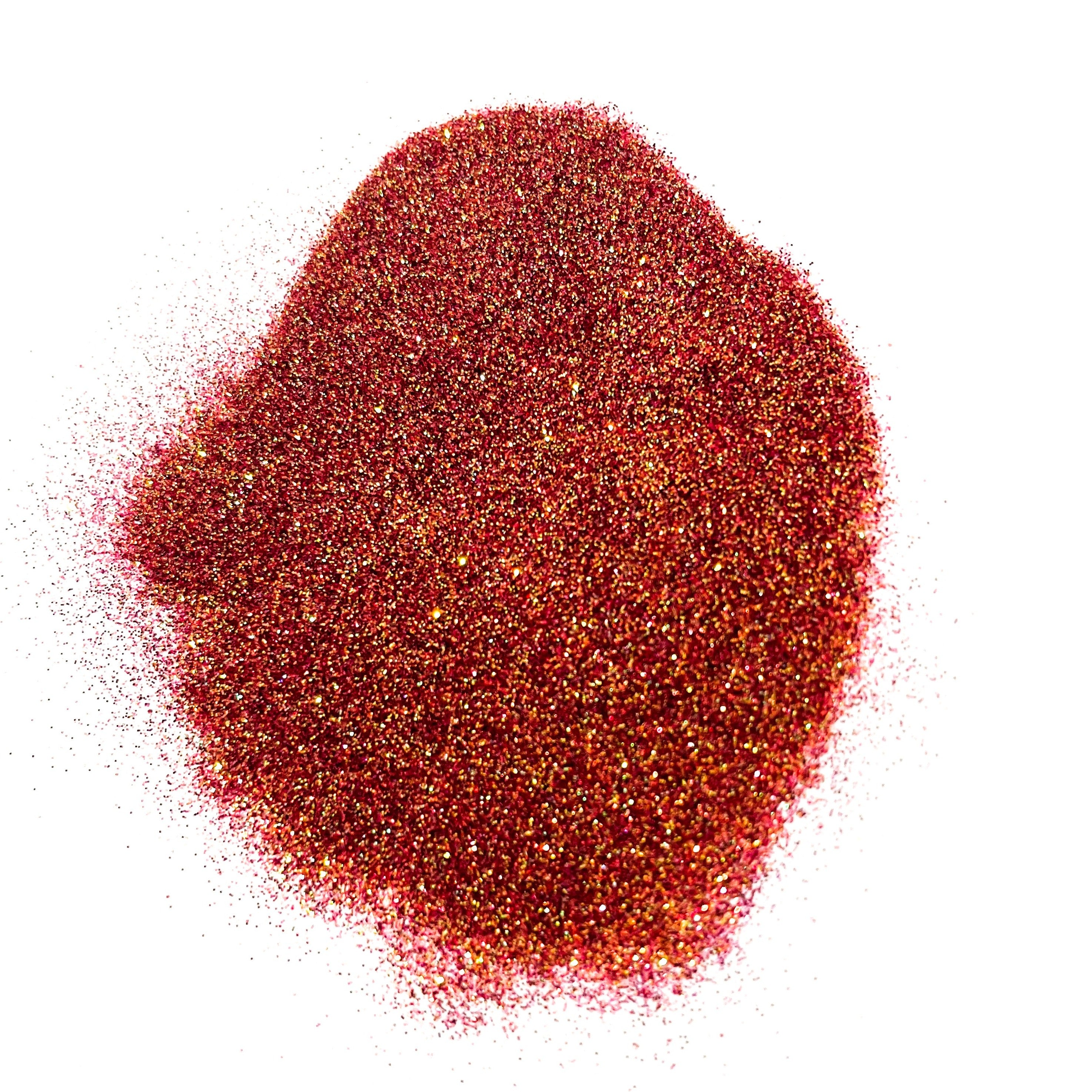 A pile of glitter with hues of red/orange/bronze/gold on a white background.