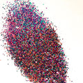 A pile of blue/purple/pink medium cut glitter on a white background.