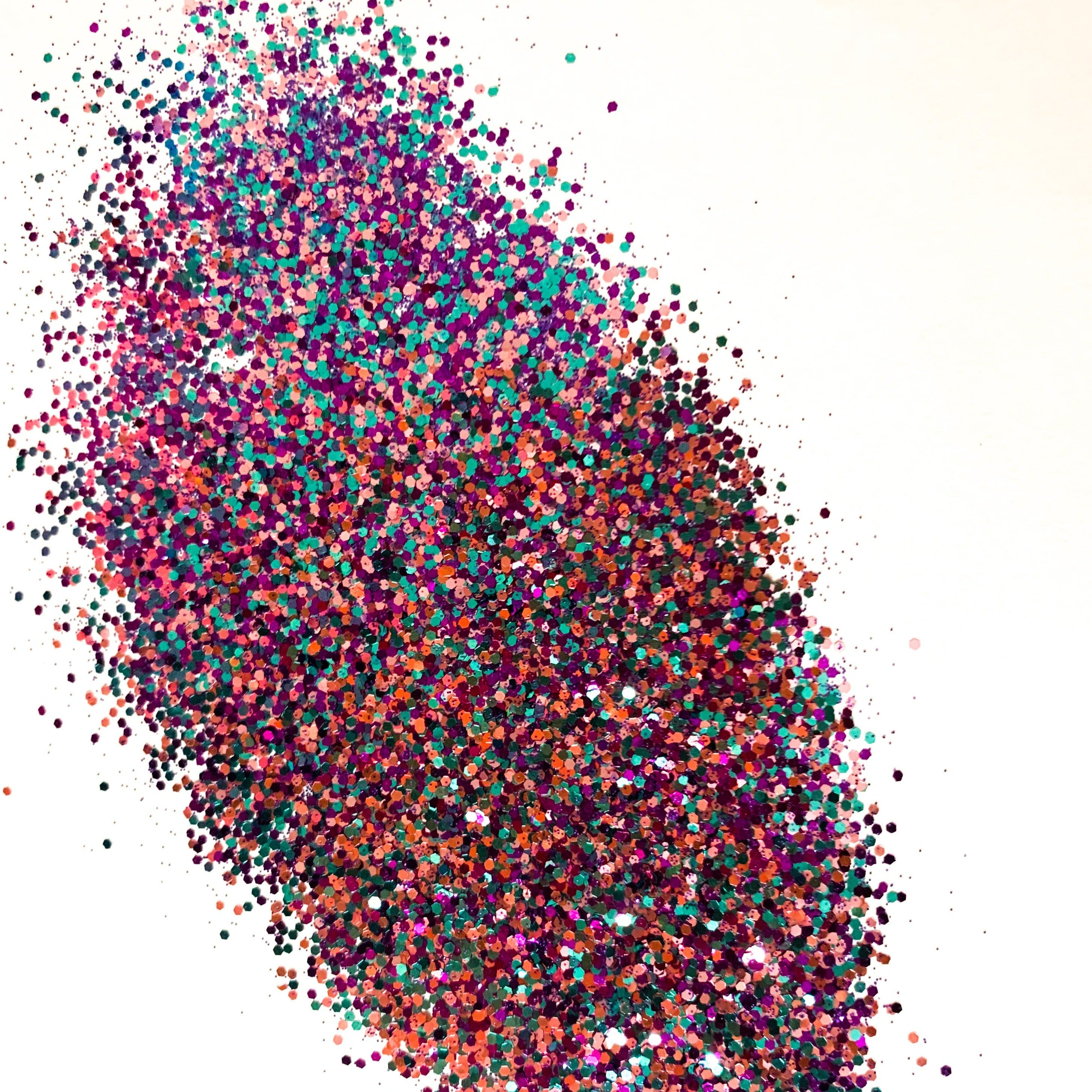 A pile of blue/purple/pink medium cut glitter on a white background.