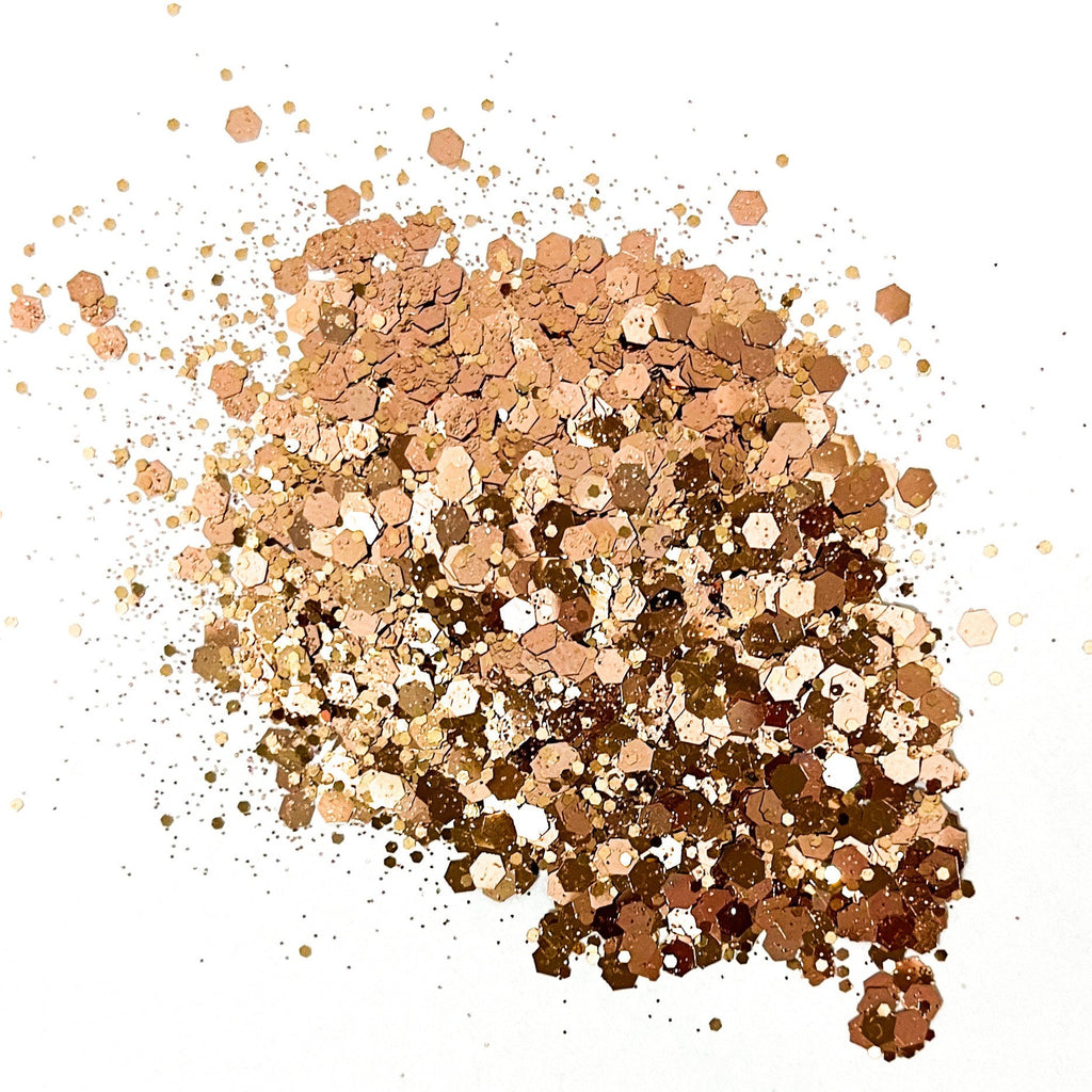 A pile of rose gold chunky glitter on a white background.