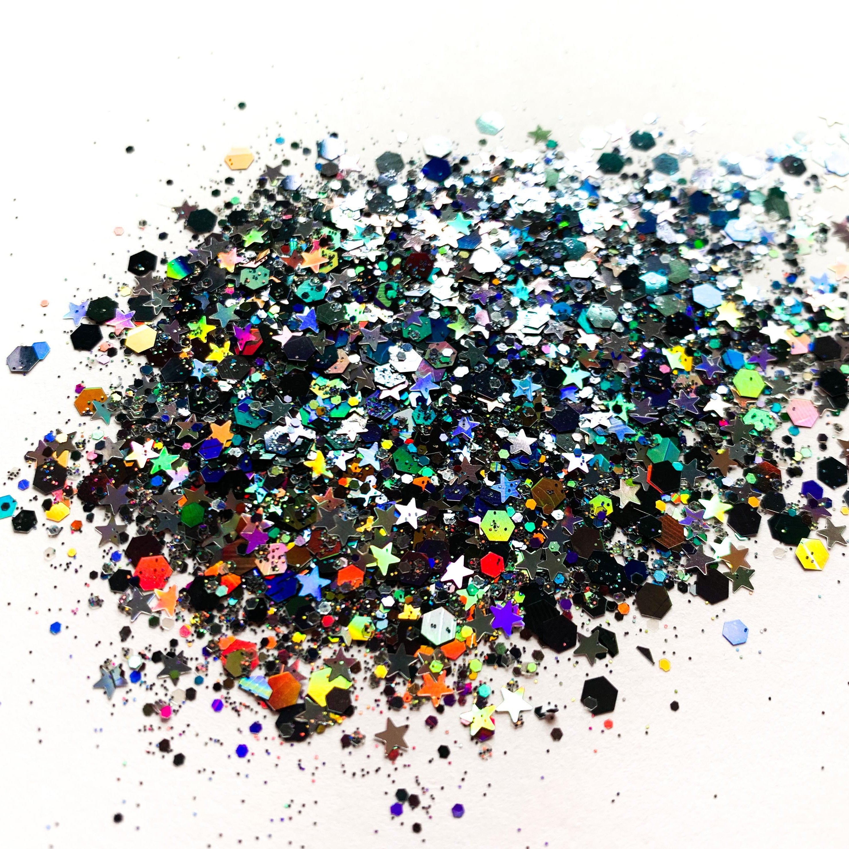 A mix of gunmetal holographic chunky glitter and star shapes spread on a surface.