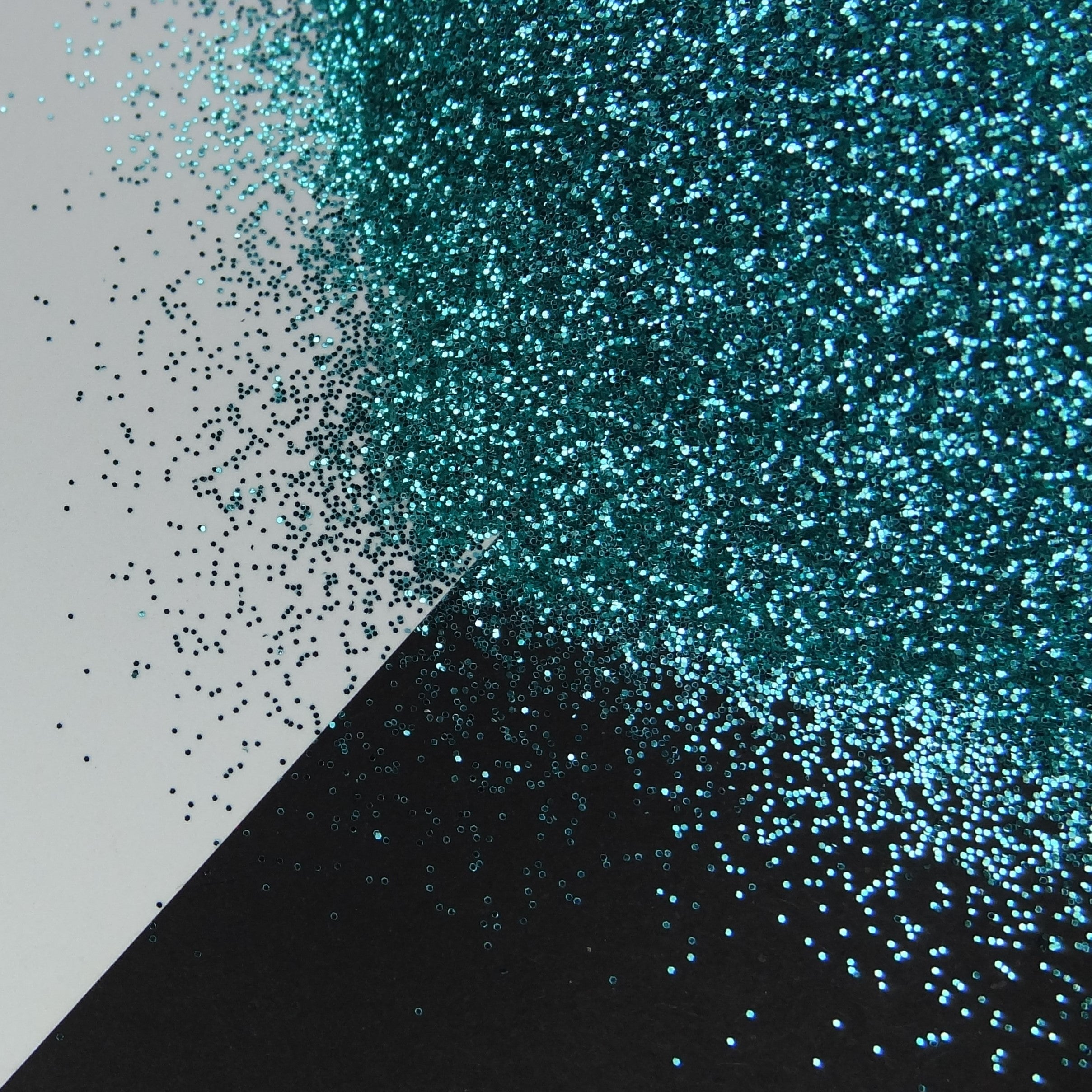A light turquoise extra fine glitter spread out on a black and white background.