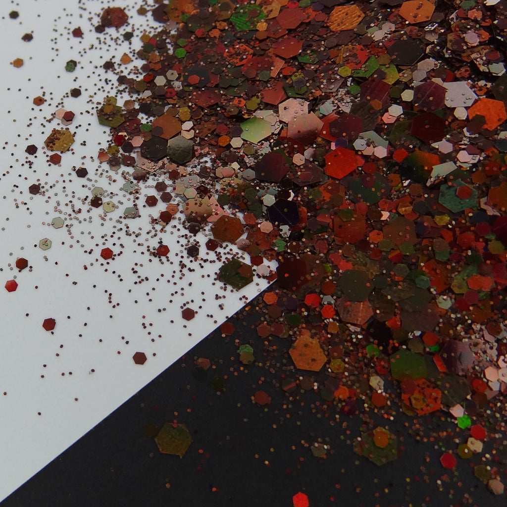 A brown holographic chunky glitter mix spread out on a black and white background.