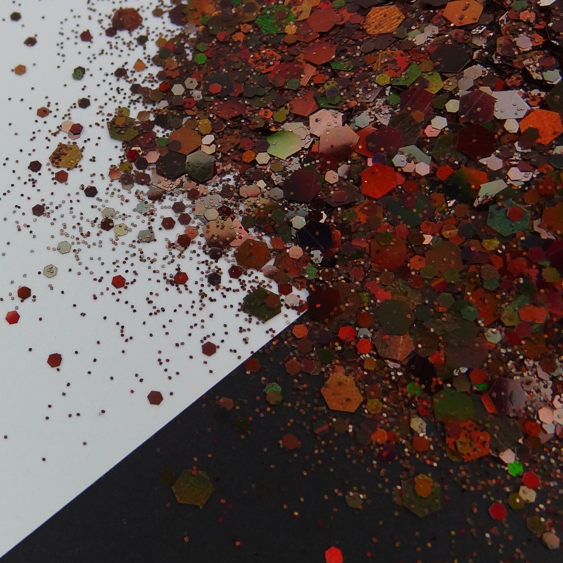 A brown holographic chunky glitter mix spread out on a black and white background.