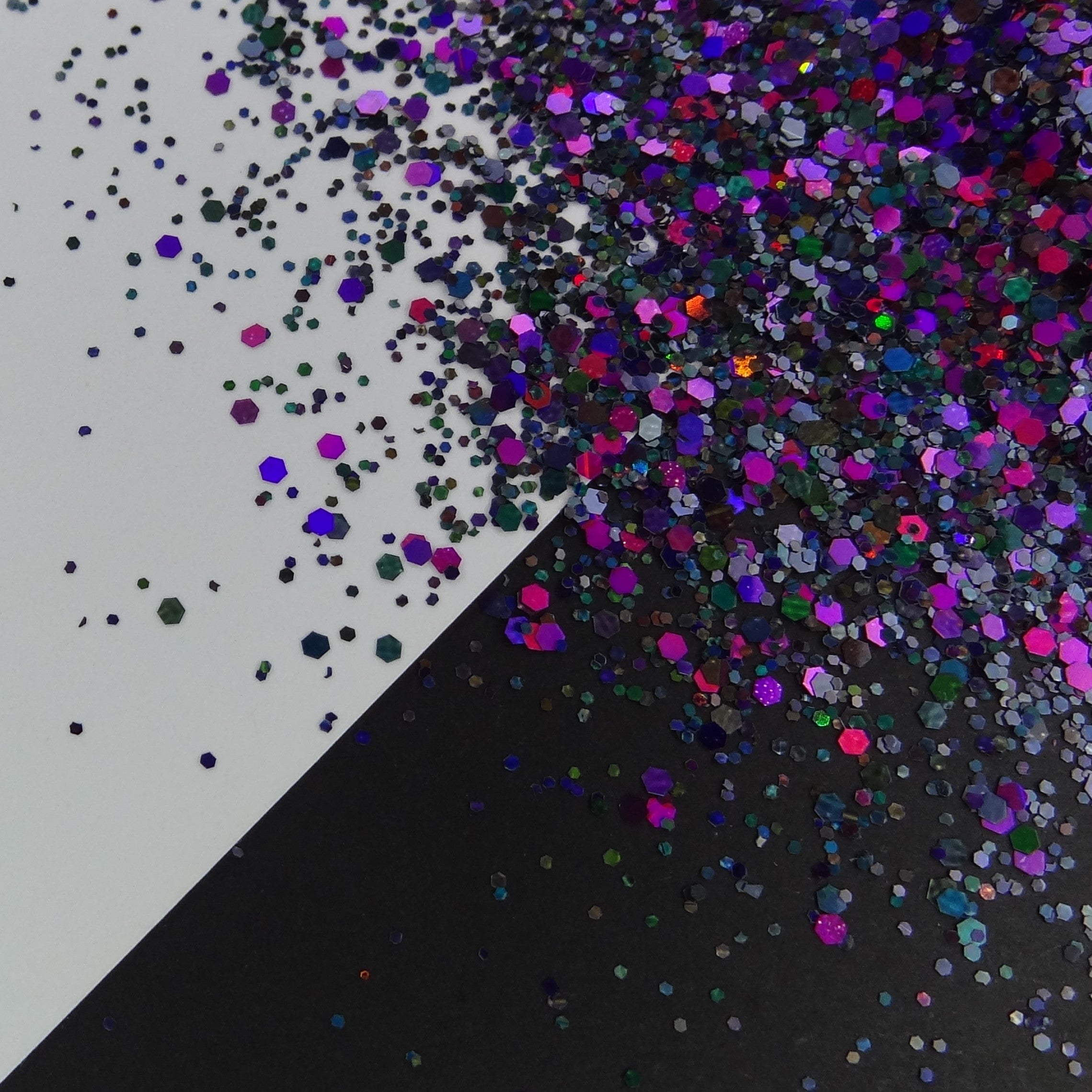 A black and purple medium holographic glitter mix spread out on a black and white background.