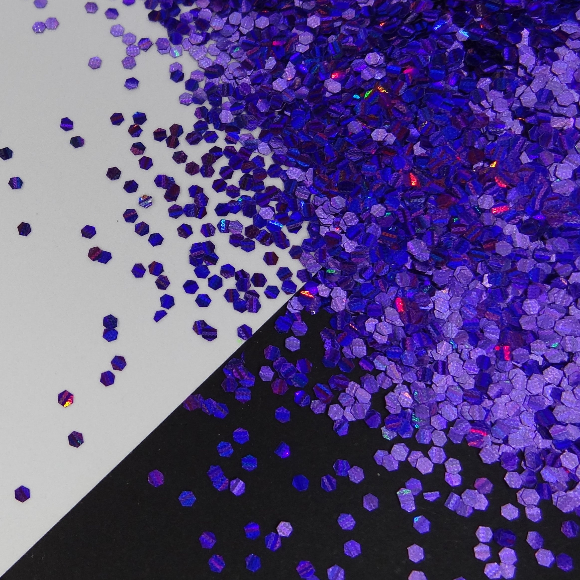 A purple holographic medium glitter mix spread out on a black and white background.