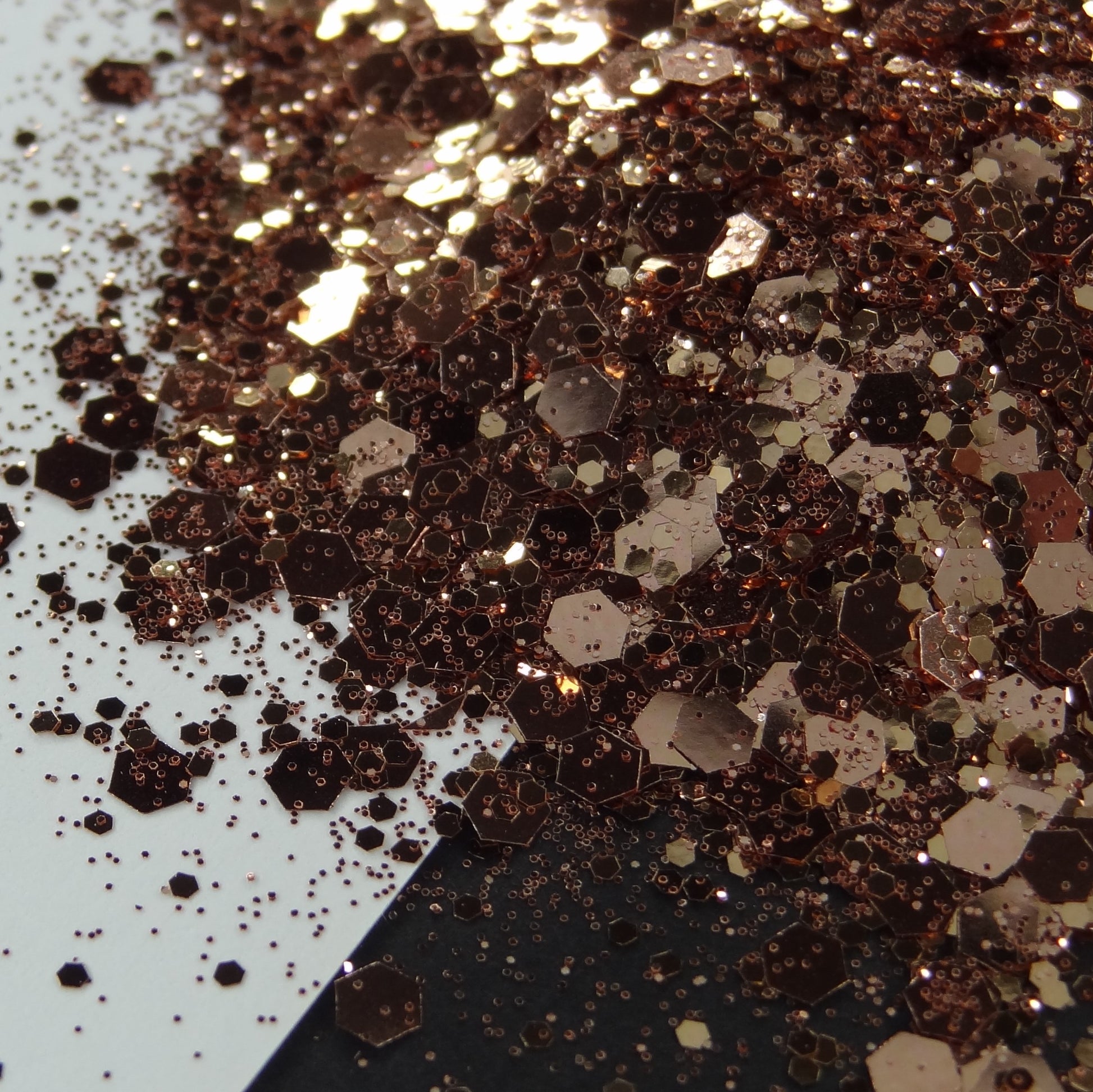 A pile of rose gold chunky glitter on a black and white background.