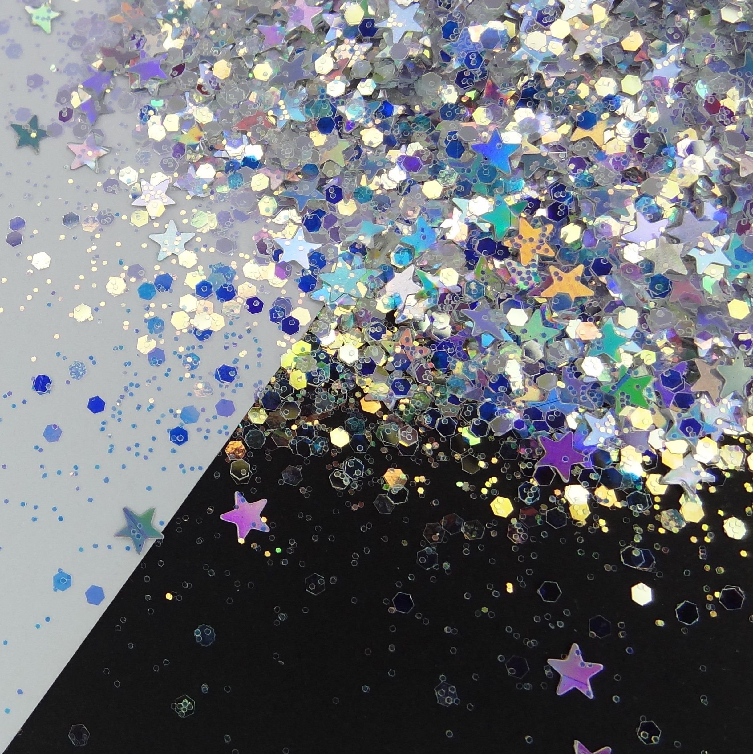 A silver holographic chunky glitter mix with stars, spread out on a black and white background.