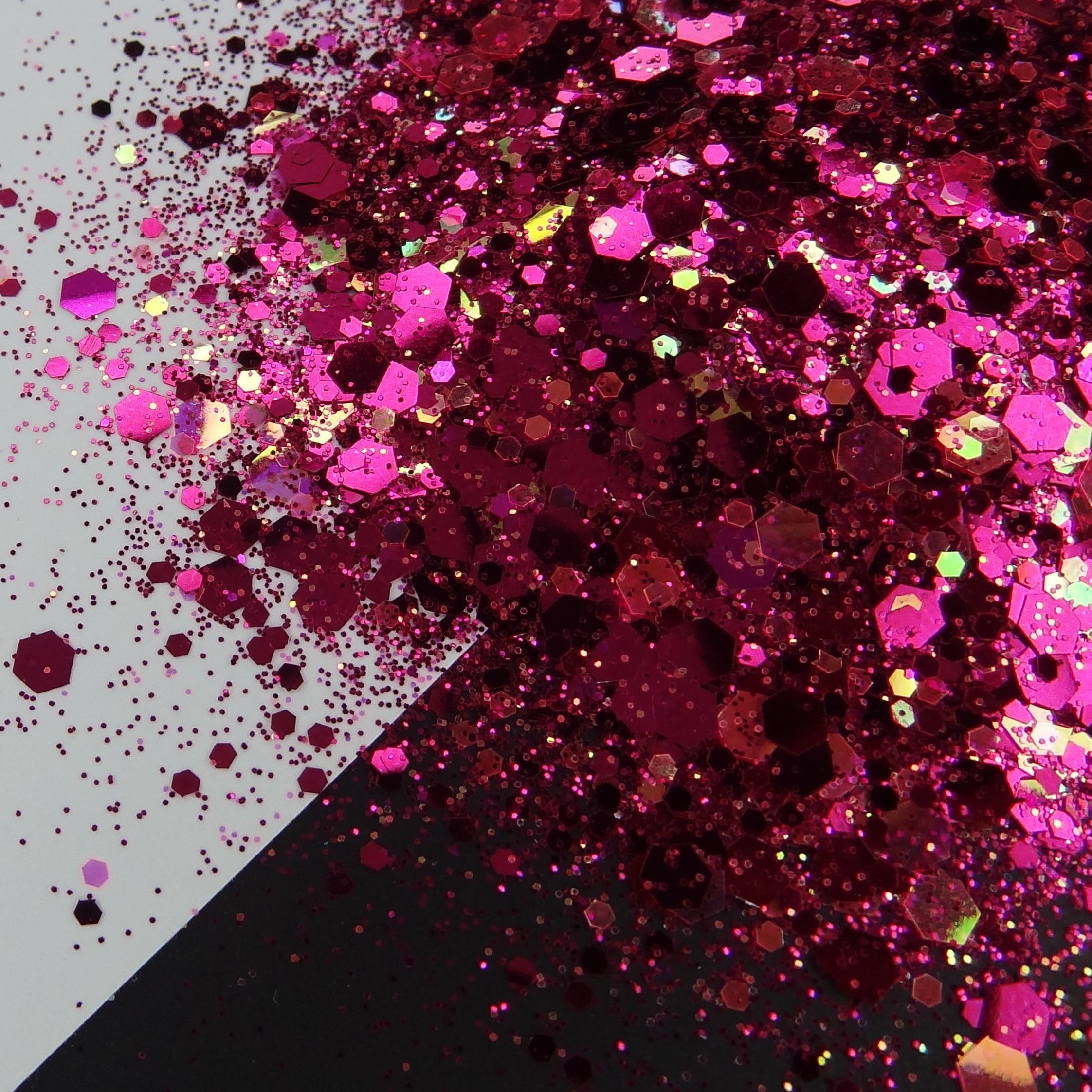 A pile of pink chunky glitter on a white and black background.