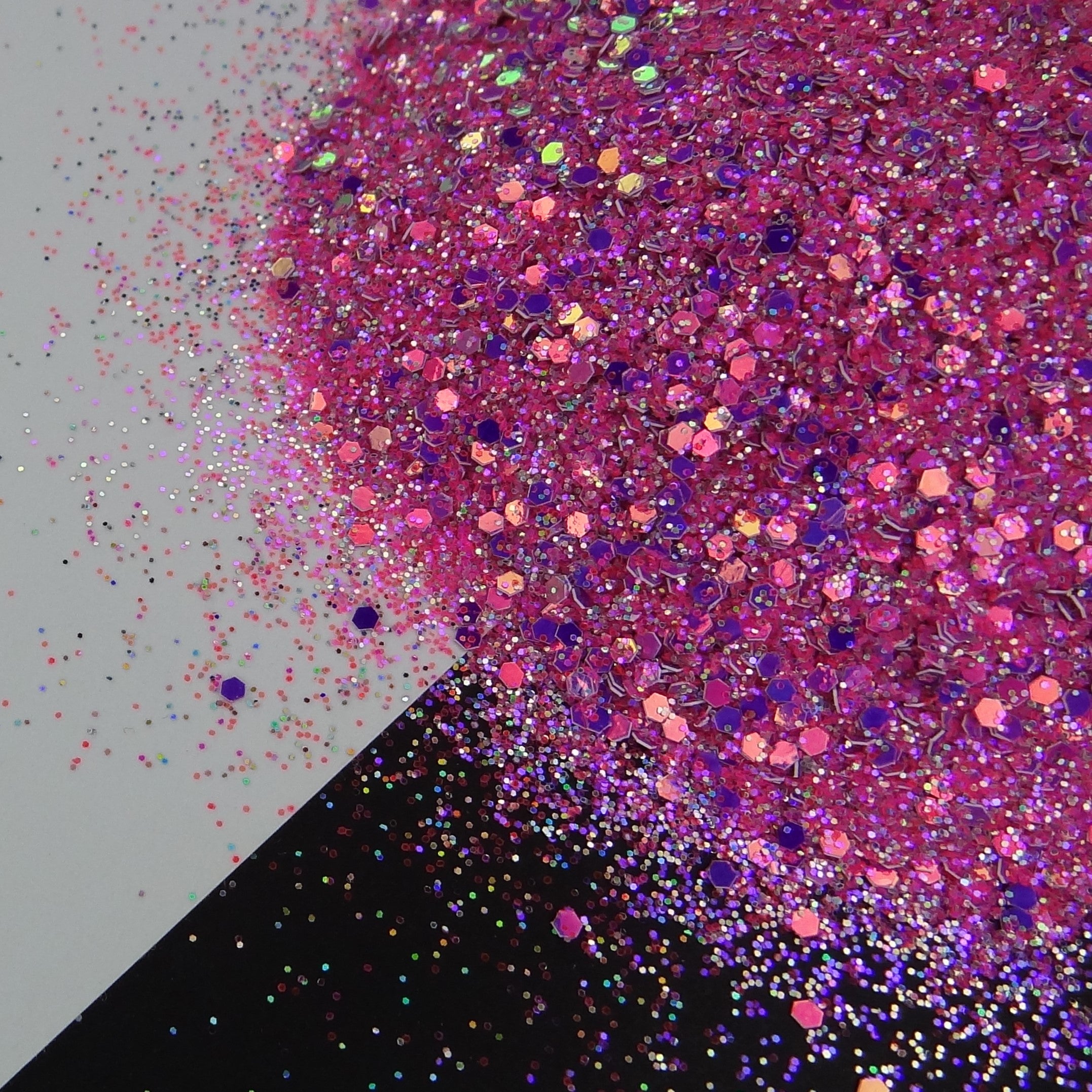 A pink and purple medium glitter mix spread out on a black and white background.