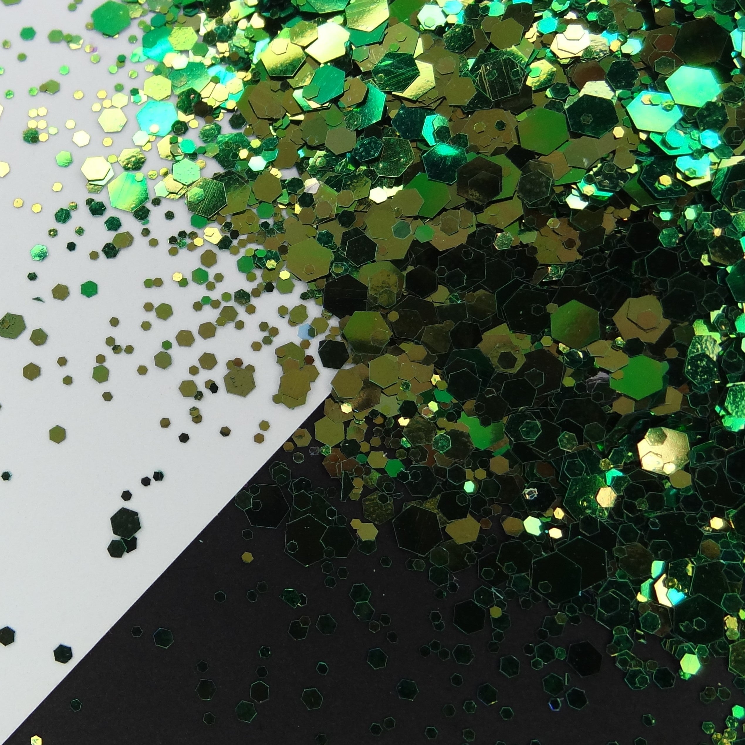 A pile of Green/Gold chameleon colour shift glitter, on a white and black background.