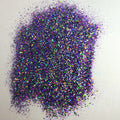 A pile of multicolored glitter, with a predominance of purple hues, spread out on a surface.