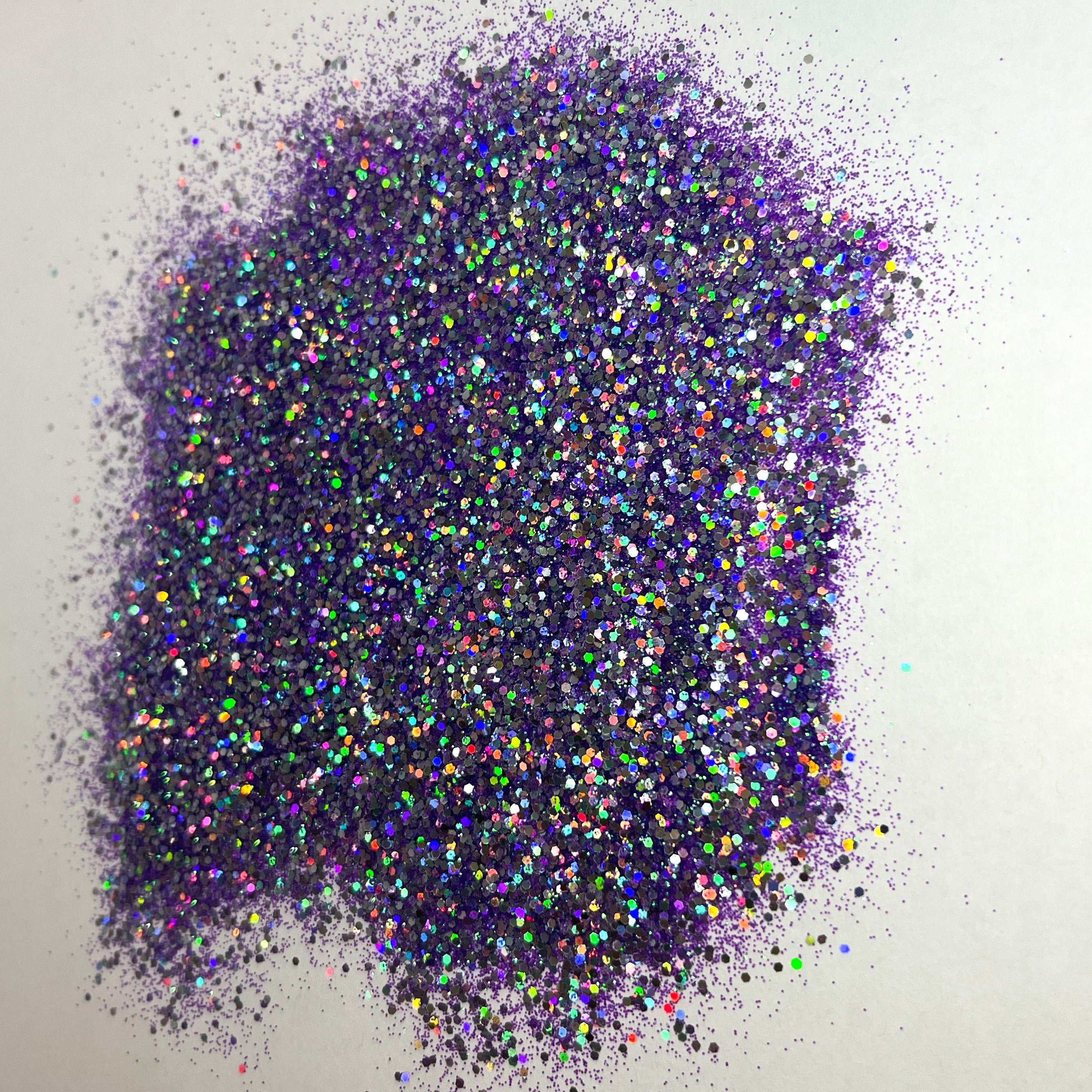 A pile of multicolored glitter, with a predominance of purple hues, spread out on a surface.