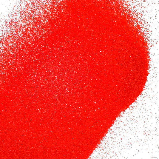 A close-up image of red metallic glitter spread on a white background.