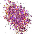 A colorful mix of purple, yellow, and multicolored chunky glitter spread on a white background.