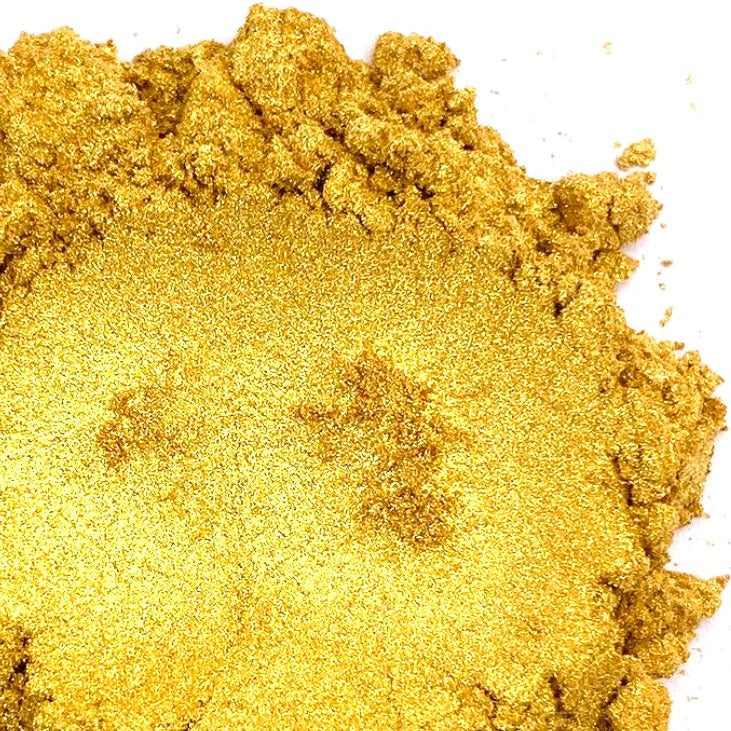A pile of gold mica powder on a white background.