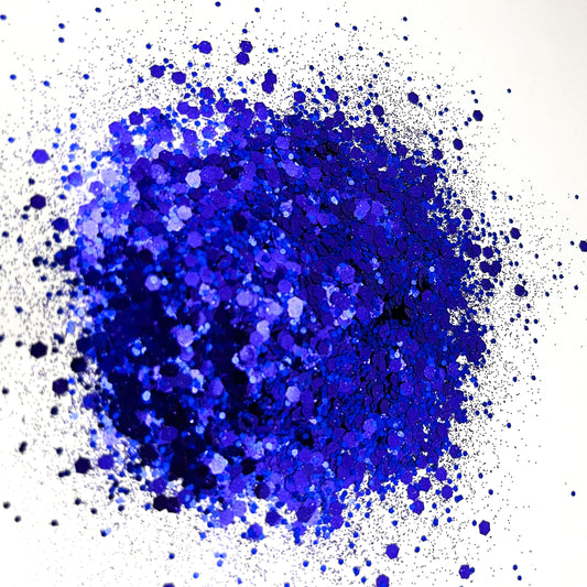 A pile of indigo chunky glitter on a white background.