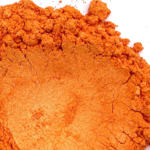 A pile of orange mica powder on a white background.
