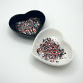 Two heart shaped containers, one black, one white, containing a Red/White/Black chunky glitter mix.