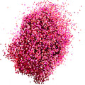 A pile of pink/gold/orange, medium glitter spread on a white surface.