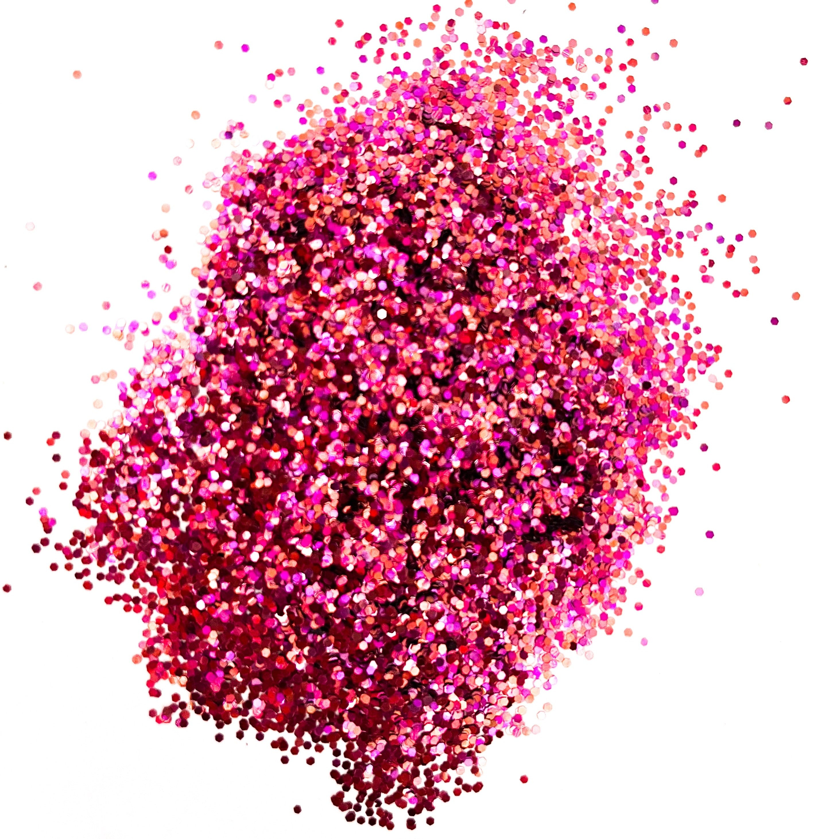 A pile of pink/gold/orange, medium glitter spread on a white surface.
