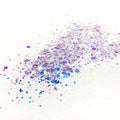 A scattered glitter mix of various sizes with colors ranging from white reflecting, blue, pink, to purple on a white background.