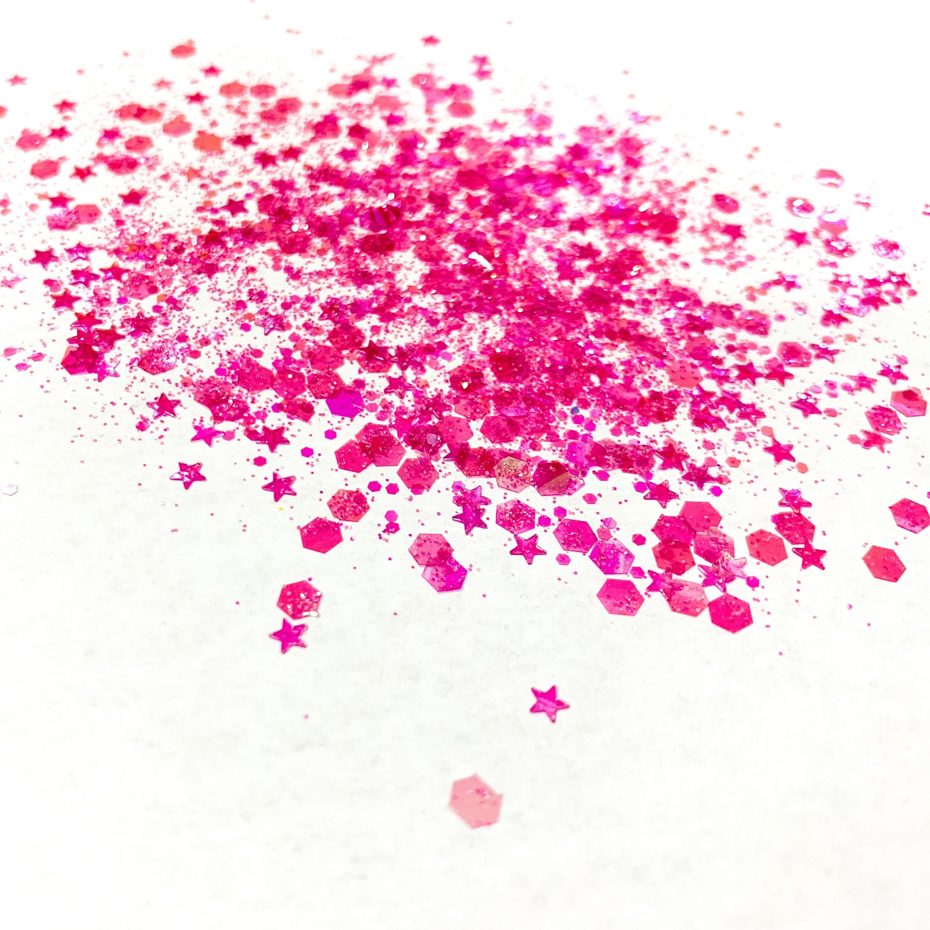 A scattered glitter mix of pink hues with star shapes on a white background.