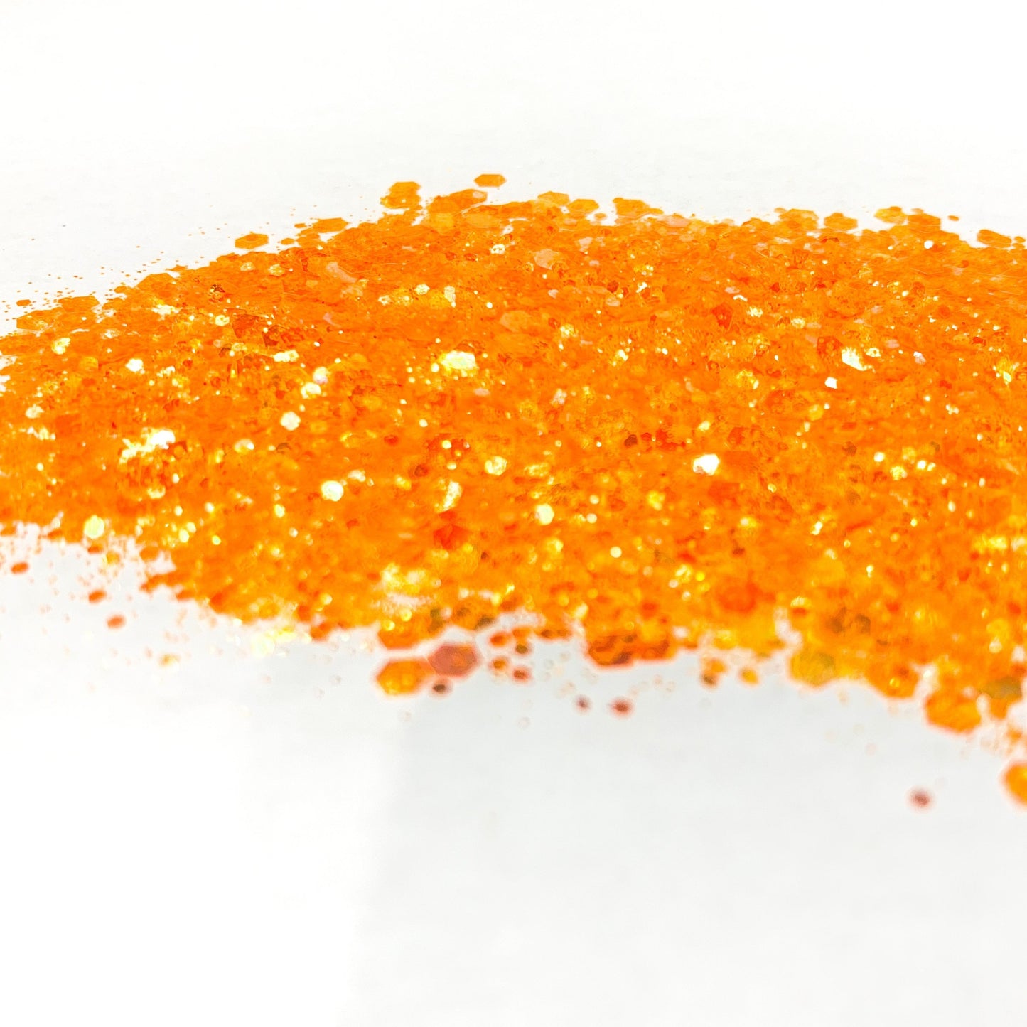 A pile of orange chunky glitter on a white background.