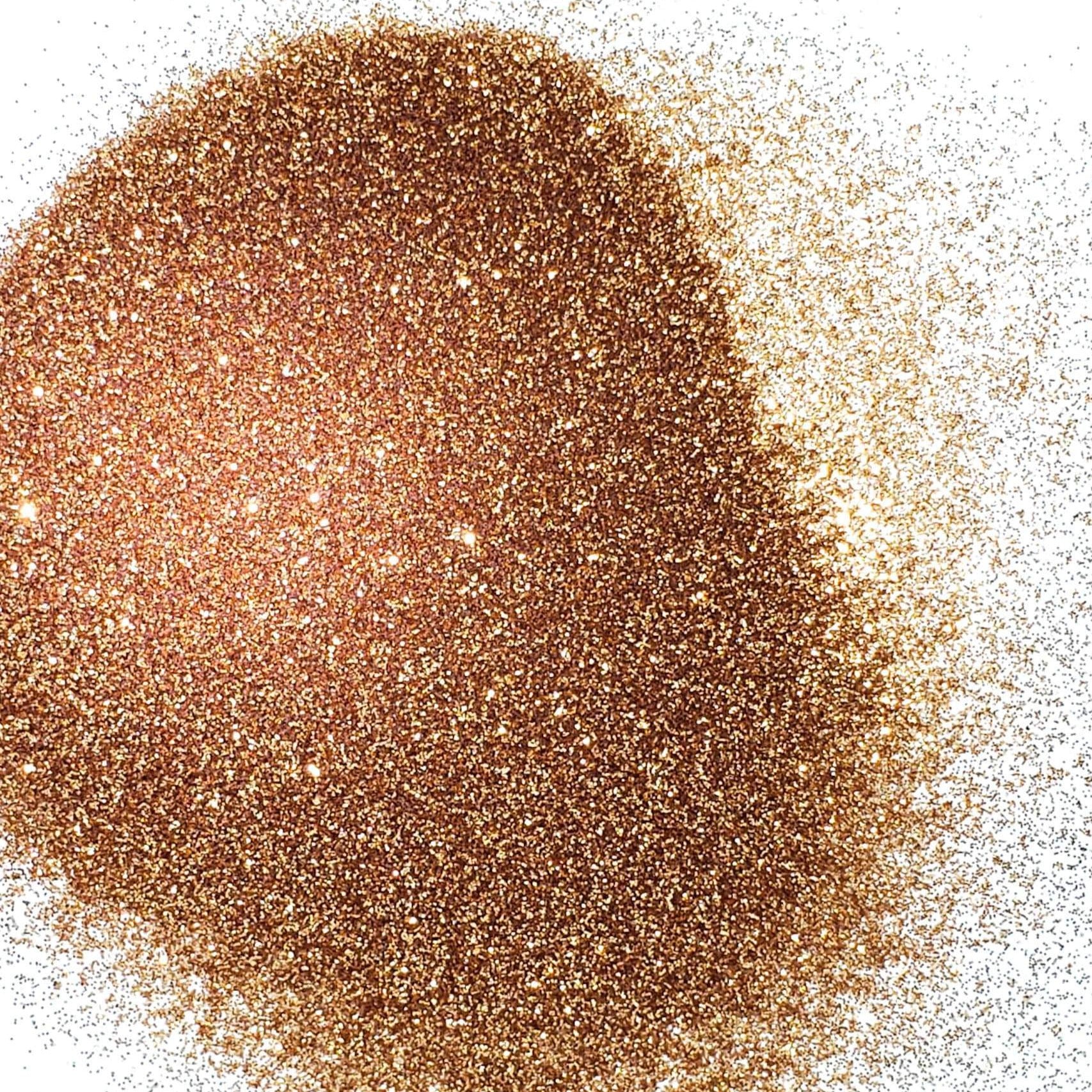 A pile of rose gold colored extra fine glitter on a white background