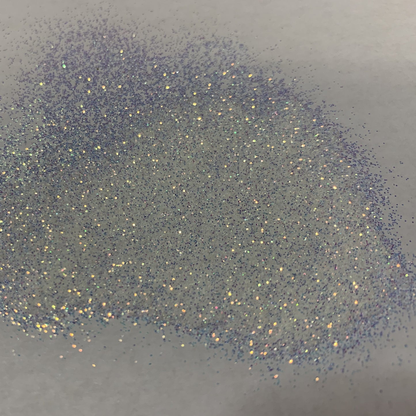 A close-up image of extra fine opal glitter spread on a surface, showing the glitter's iridescent properties and the true color of the product.