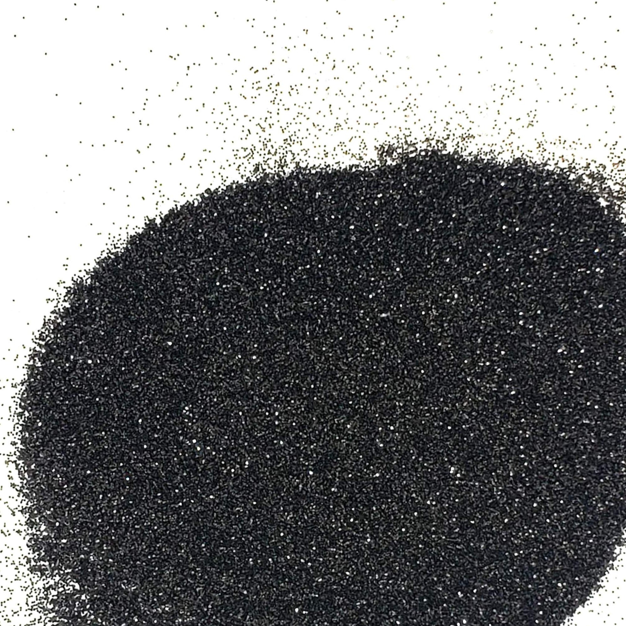 A close-up image of black extra fine glitter spread out on a surface.