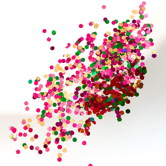 A pile of XL cut glitter in purple, green, gold and pink colours on a white background.