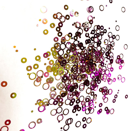 A purple/gold chameleon colour shift hollow circle glitter on a white background.