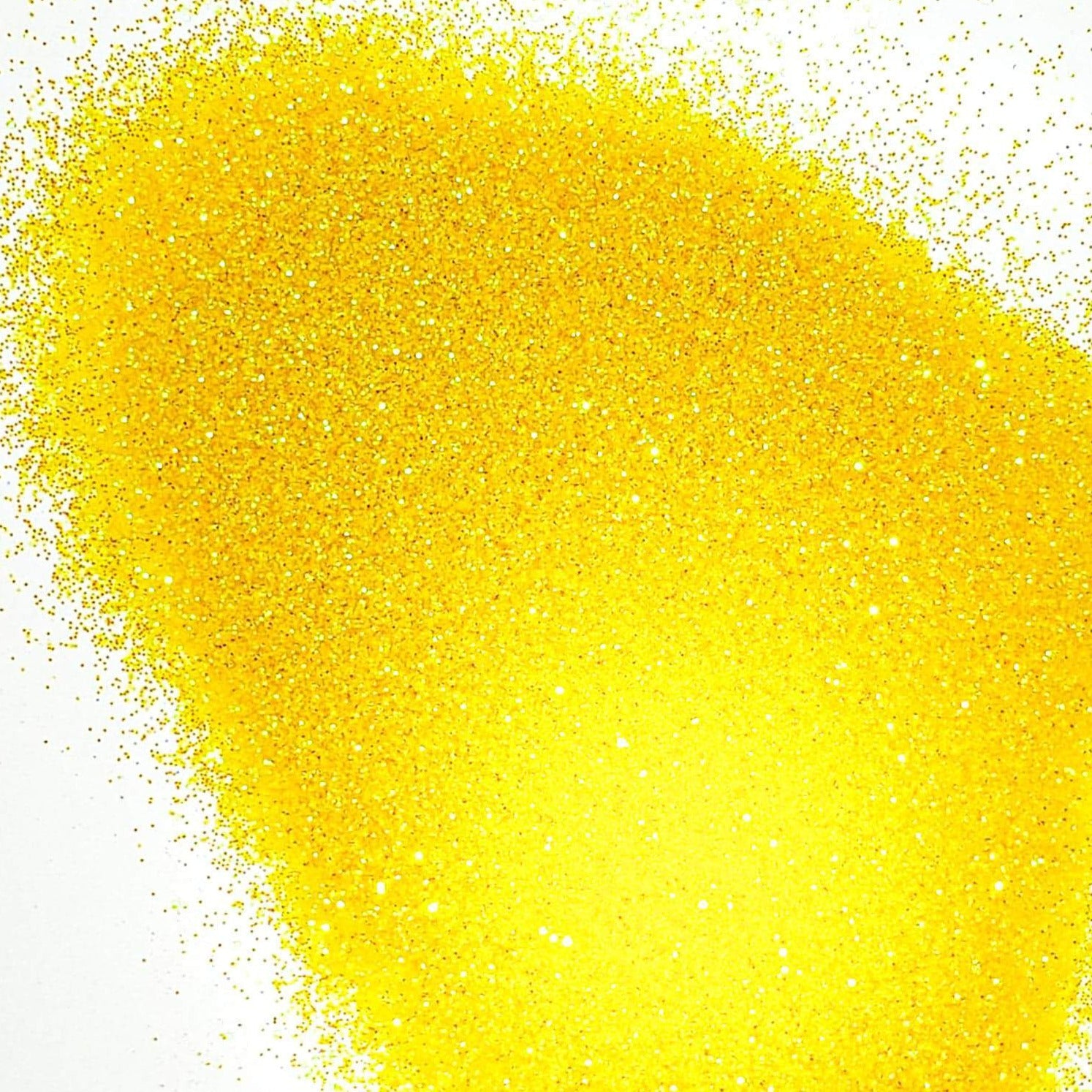 A pile of yellow, extra fine, iridescent glitter against a white background