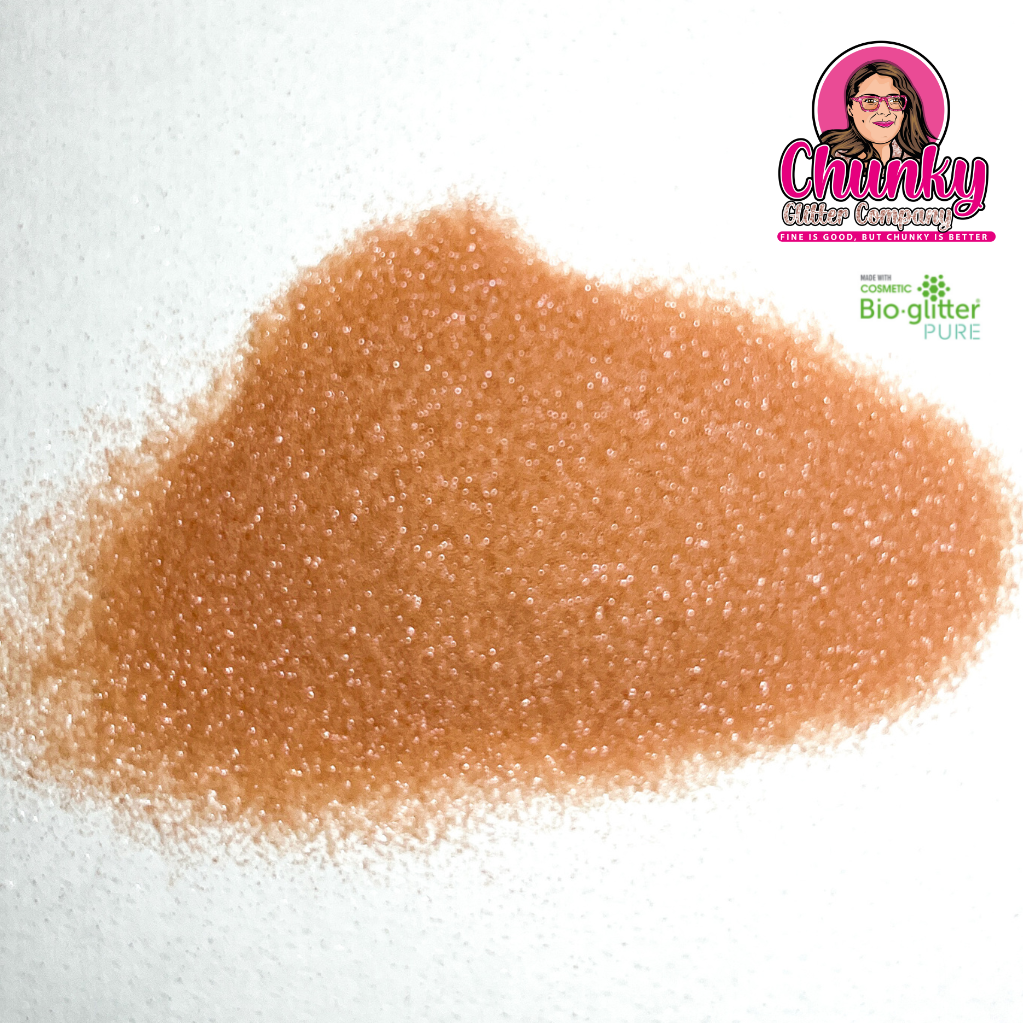 A pile of rose pink iridescent biodegradable glitter on a white surface with a logo in the corner.