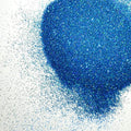 A pile of blue holographic glitter, in extra fine on a white background.