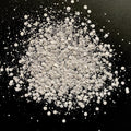A pile of white chunky glitter on a black background