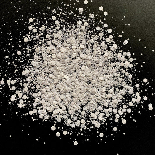 A pile of white chunky glitter on a black background