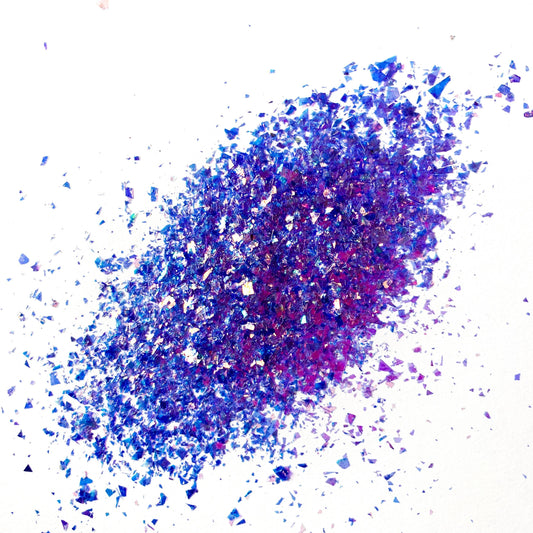 A pile of purple irregular glitter flakes spread out on a white background.