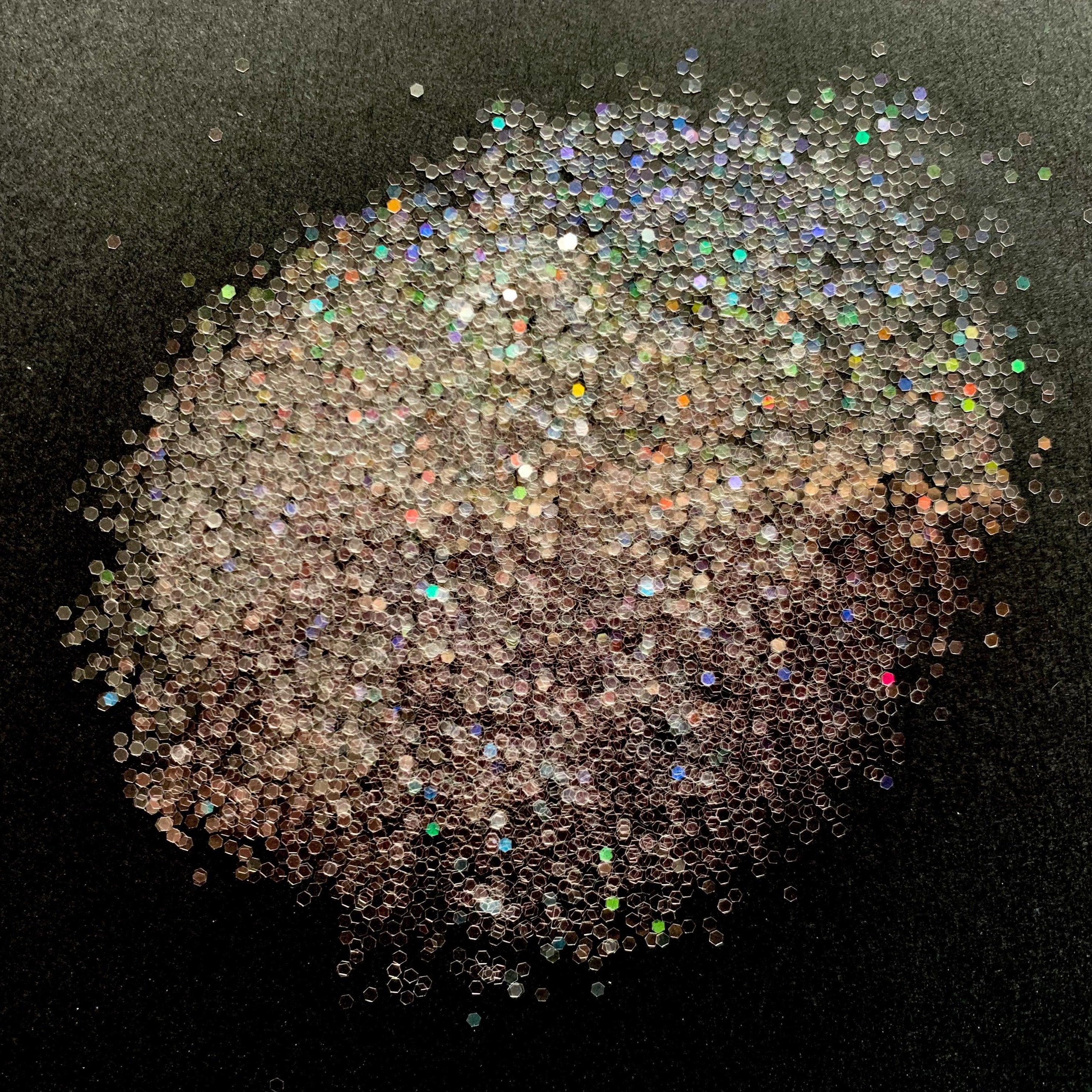 A pile of clear holographic glitter, showing various sizes of reflective particles.