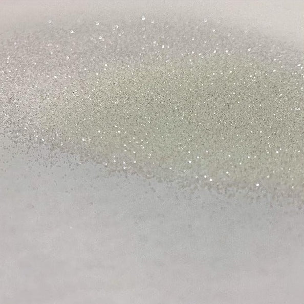 A close-up image of white glitter spread out on a surface, showing the texture and sparkle of the product.